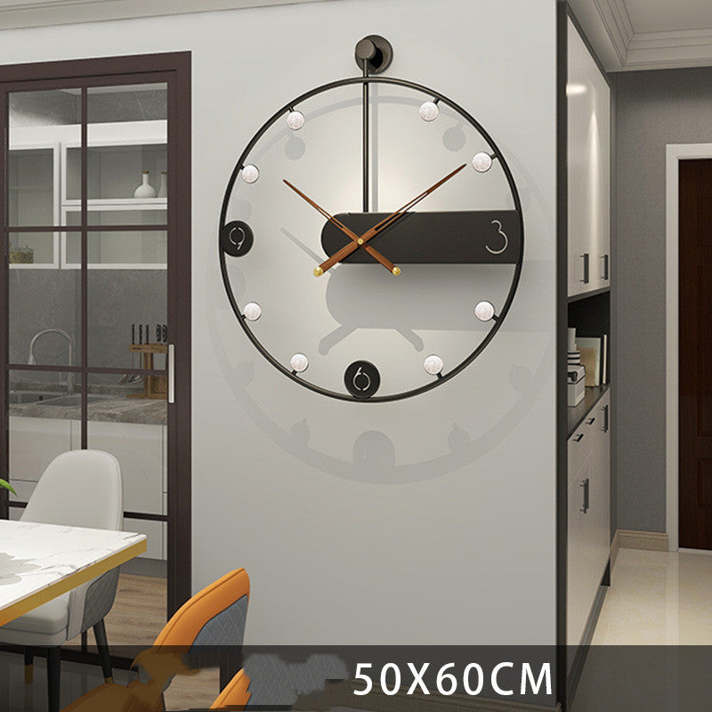 Modern wall clock on a gray wall with a dining area in the background