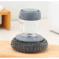 Cleaning brush with gray handle and metal scrubber on a wooden surface