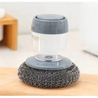 Cleaning brush with gray handle and metal scrubber on a wooden surface