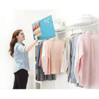 Woman organizing clothes in a closet using a blue folding board.