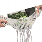 Metal colander with brussels sprouts being rinsed under water on a white background
