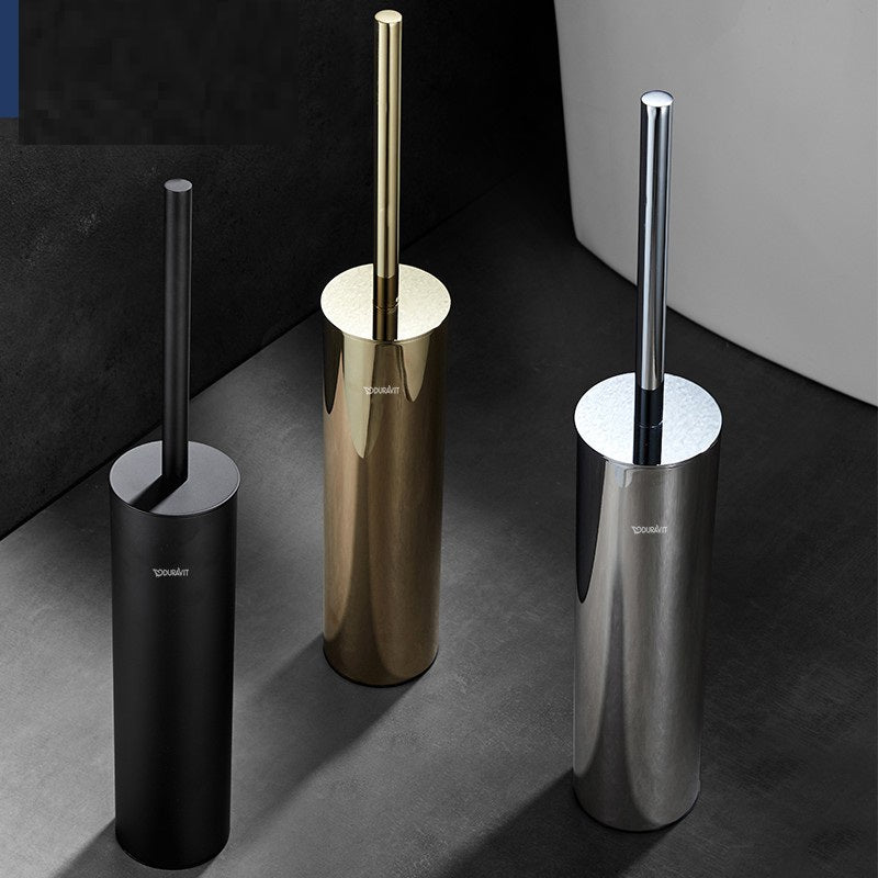 Three toilet brushes in black, gold, and silver stands on a dark surface.