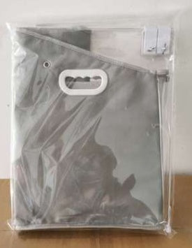 Black bag with a handle in clear plastic packaging on a wooden surface