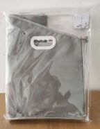 Black bag with a handle in clear plastic packaging on a wooden surface