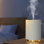 White humidifier emitting steam on a wooden surface with a blurred bedroom background