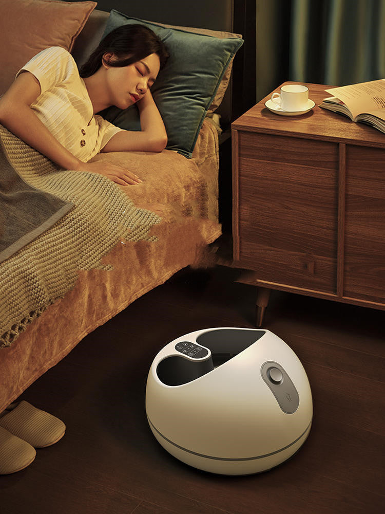 Woman lying in bed with a foot massager on the floor next to her.